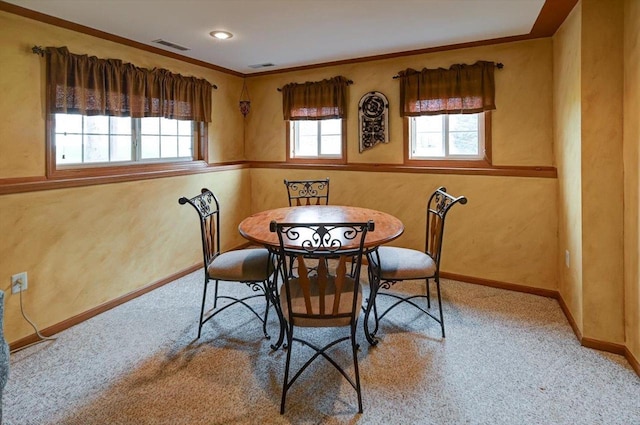 dining room featuring baseboards, ornamental molding, visible vents, and light carpet