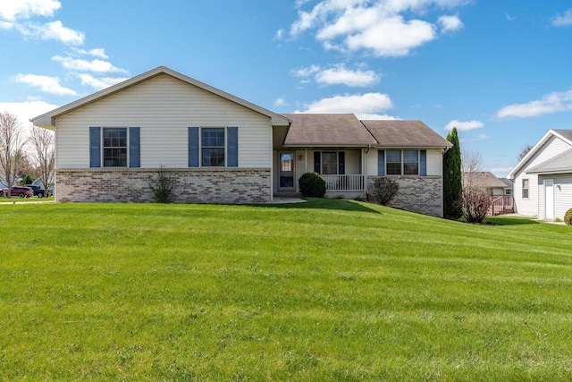 view of front of house with brick siding, a front lawn, and covered porch