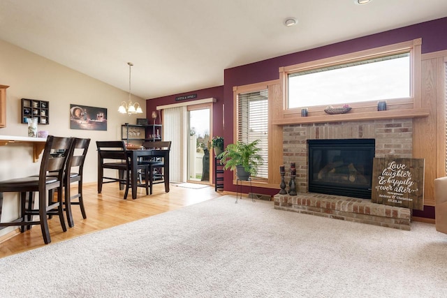 living room featuring visible vents, a brick fireplace, a chandelier, wood finished floors, and vaulted ceiling