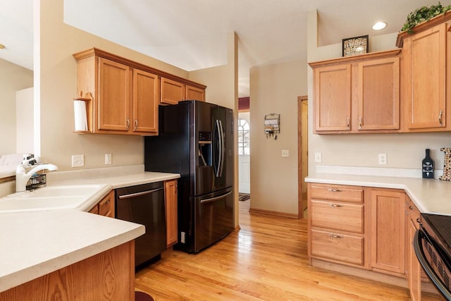 kitchen featuring a sink, dishwasher, range, black refrigerator with ice dispenser, and light wood-type flooring