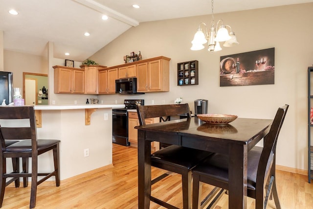kitchen with a breakfast bar area, light countertops, black appliances, light wood finished floors, and vaulted ceiling with beams