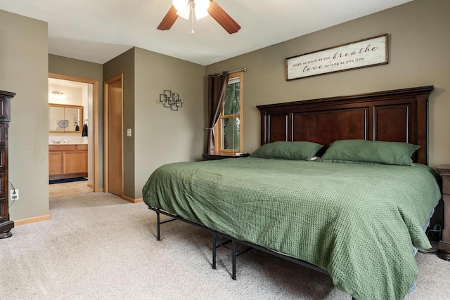 bedroom featuring light colored carpet, baseboards, ceiling fan, and ensuite bathroom