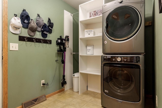 clothes washing area with laundry area, tile patterned floors, stacked washer / dryer, and visible vents