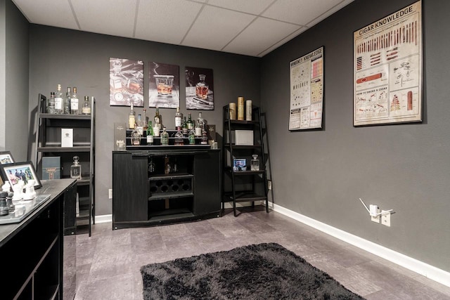 bar featuring a bar, baseboards, and a drop ceiling