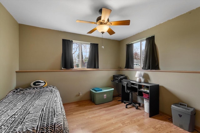 bedroom featuring ceiling fan, multiple windows, and wood finished floors