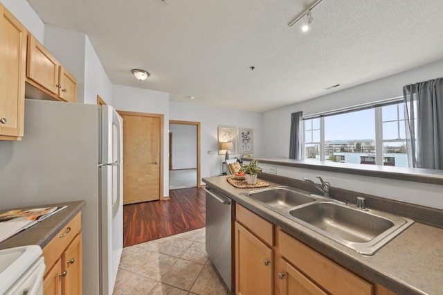 kitchen featuring stove, rail lighting, dishwasher, a sink, and freestanding refrigerator