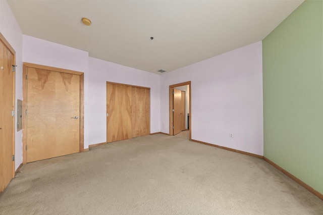 unfurnished bedroom with baseboards, light carpet, a closet, and electric panel