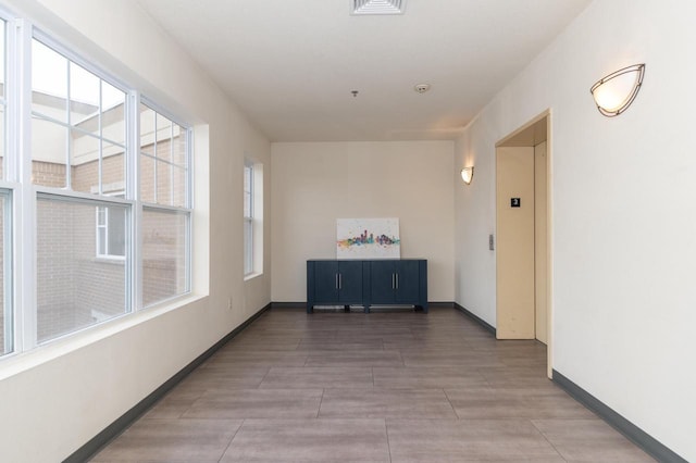 corridor featuring elevator and baseboards