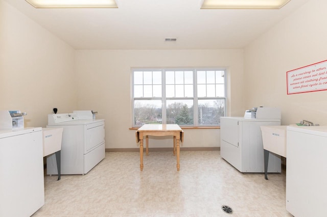 shared laundry area featuring separate washer and dryer, baseboards, visible vents, and light floors