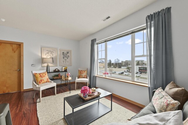 living room featuring baseboards, visible vents, and wood finished floors