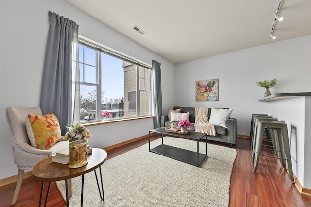 living room with track lighting, baseboards, wood finished floors, and visible vents