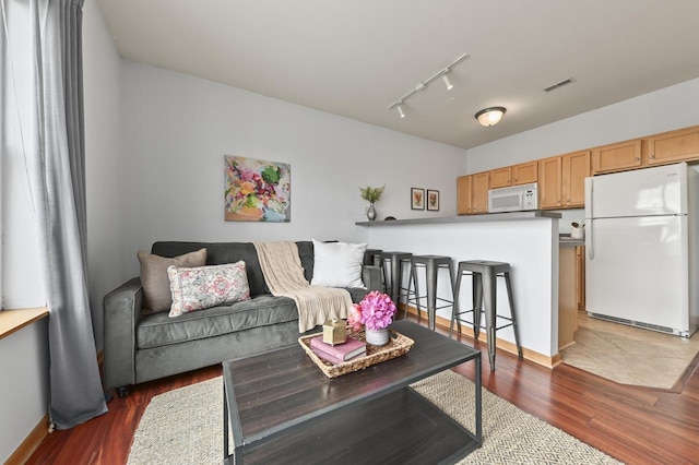 living room featuring baseboards, visible vents, track lighting, and wood finished floors