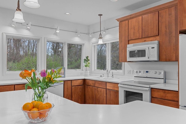 kitchen featuring a sink, light countertops, brown cabinets, and white appliances