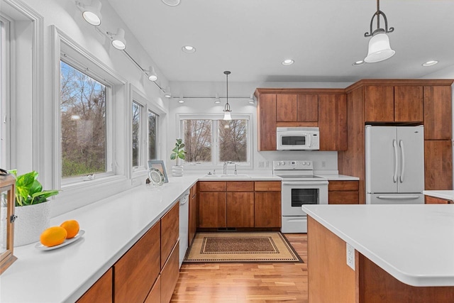 kitchen with brown cabinets, white appliances, light countertops, recessed lighting, and light wood-type flooring