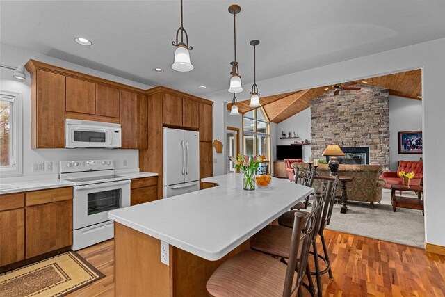 kitchen featuring brown cabinetry, lofted ceiling, a wealth of natural light, and white appliances
