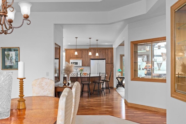 dining room with baseboards, a notable chandelier, and wood finished floors