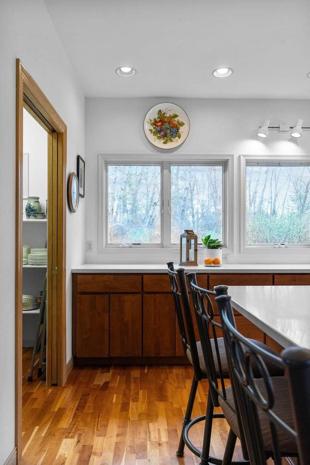 kitchen with light countertops, recessed lighting, brown cabinetry, and light wood-style floors