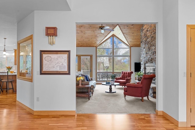 living area with baseboards, ceiling fan, wood finished floors, and lofted ceiling