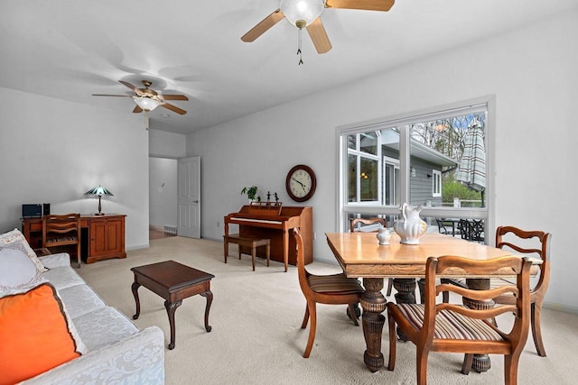dining space with ceiling fan and light carpet