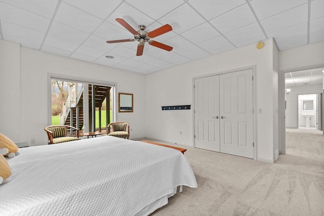 carpeted bedroom featuring a closet, a ceiling fan, and a drop ceiling