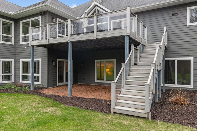 back of house featuring roof with shingles, a wooden deck, and stairway