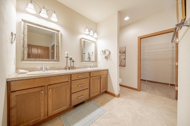 full bath with a sink, toilet, double vanity, and a spacious closet