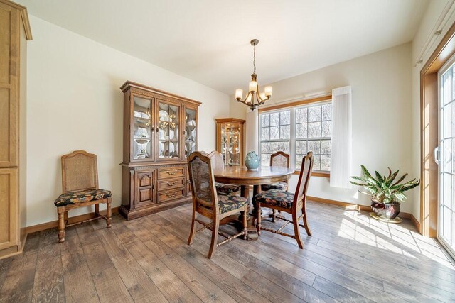dining space with a healthy amount of sunlight, hardwood / wood-style flooring, and a notable chandelier