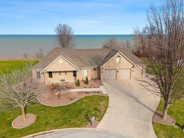 view of front facade with a garage, a water view, driveway, and a front yard