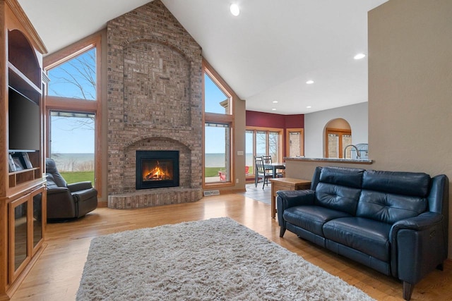 living area featuring visible vents, wood finished floors, a fireplace, high vaulted ceiling, and recessed lighting