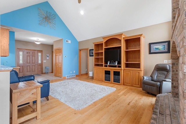 living room featuring high vaulted ceiling, visible vents, and light wood finished floors