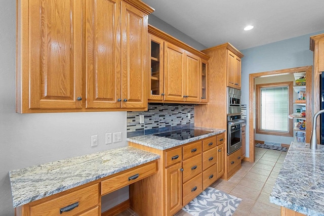 kitchen with glass insert cabinets, stainless steel oven, black electric stovetop, tasteful backsplash, and light stone counters