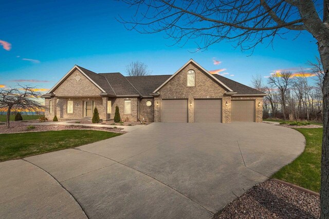 view of front facade featuring a shingled roof, a front lawn, brick siding, a garage, and driveway