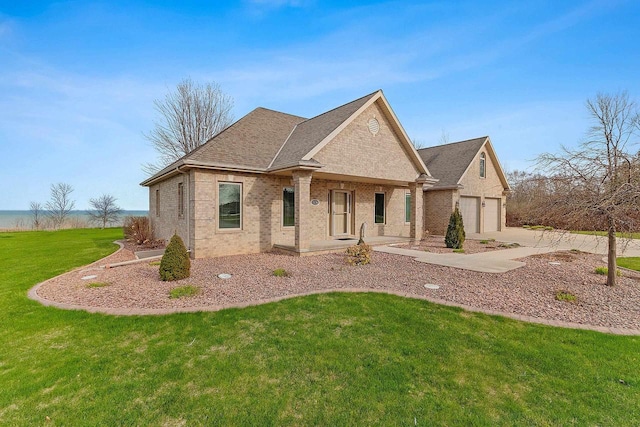 french country home with a porch, a front yard, a garage, brick siding, and concrete driveway