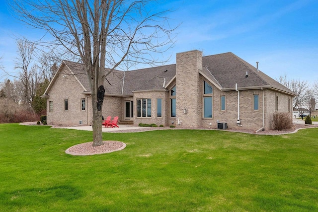 rear view of property featuring a patio, a chimney, brick siding, a lawn, and central air condition unit