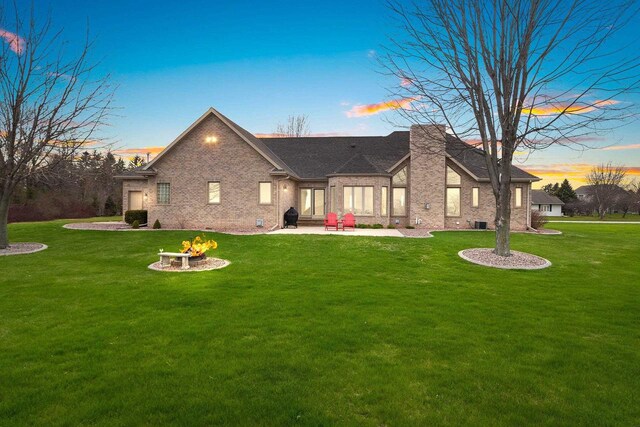 exterior space with a lawn, brick siding, a fire pit, and a patio