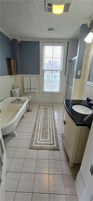 422 W Columbia St, Chippewa Falls, WI 54729 - bathroom with crown molding, wainscoting, a decorative wall, and tile patterned flooring