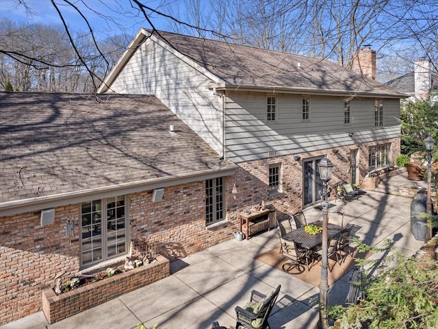 19425 Killarney Way, Brookfield, WI 53045 - back of house with a chimney, outdoor dining area, roof with shingles, brick siding, and a patio