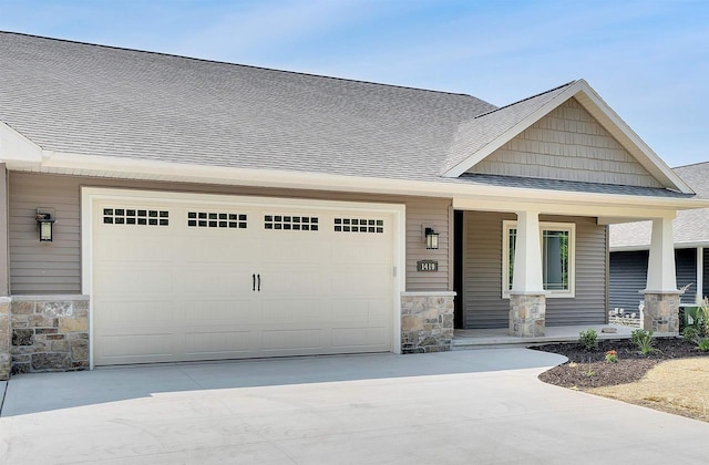 craftsman house with covered porch, roof with shingles, a garage, concrete driveway, and stone siding