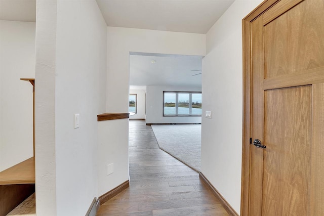 hall with baseboards and wood finished floors