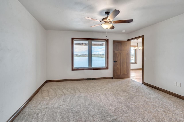 spare room with baseboards, carpet flooring, ceiling fan with notable chandelier, and visible vents