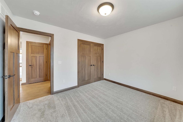unfurnished bedroom featuring baseboards, a closet, and light colored carpet
