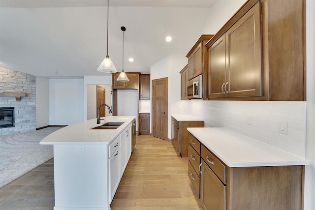 kitchen with open floor plan, a sink, light wood finished floors, decorative light fixtures, and stainless steel appliances