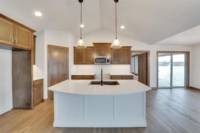 kitchen with brown cabinetry, tasteful backsplash, vaulted ceiling, a sink, and stainless steel microwave