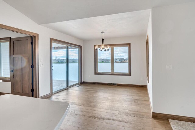 unfurnished dining area featuring baseboards, visible vents, light wood-style flooring, and a chandelier