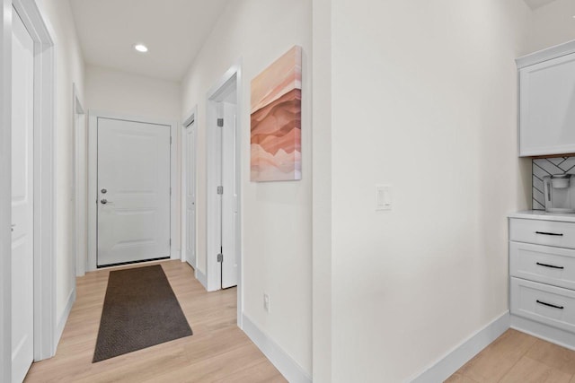 corridor featuring light wood finished floors, baseboards, and recessed lighting