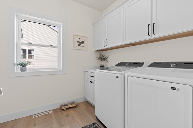 washroom with cabinet space, baseboards, light wood-type flooring, and separate washer and dryer