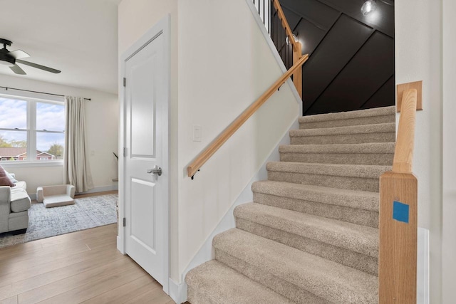 stairway with wood finished floors and a ceiling fan