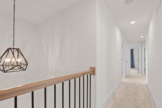 hallway with light colored carpet, recessed lighting, a chandelier, baseboards, and an upstairs landing