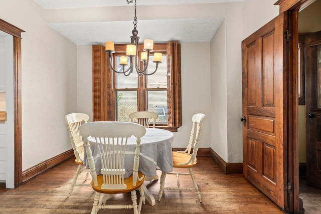 dining room with an inviting chandelier, wood-type flooring, and baseboards
