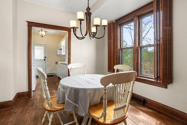 dining space featuring baseboards, wood-type flooring, a chandelier, and a wealth of natural light